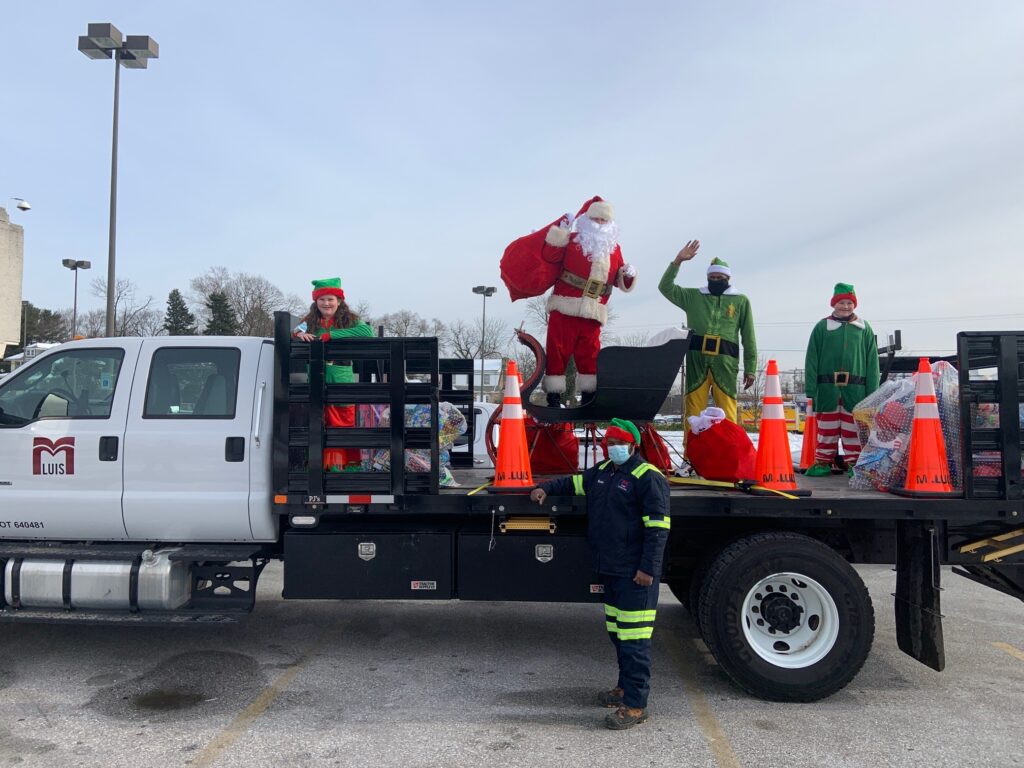 Santa, elves, driver with truckload of toys